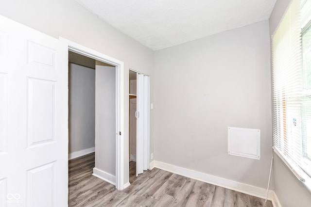 unfurnished bedroom featuring a closet, light hardwood / wood-style flooring, and multiple windows