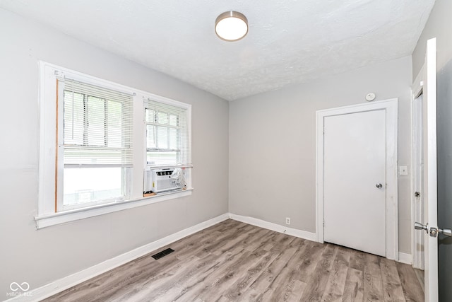 spare room with light wood-type flooring and a textured ceiling