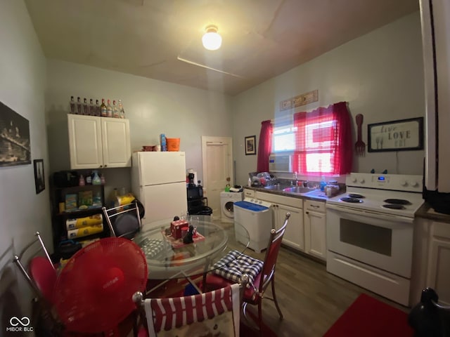 kitchen featuring white appliances, white cabinets, washer / dryer, sink, and hardwood / wood-style flooring