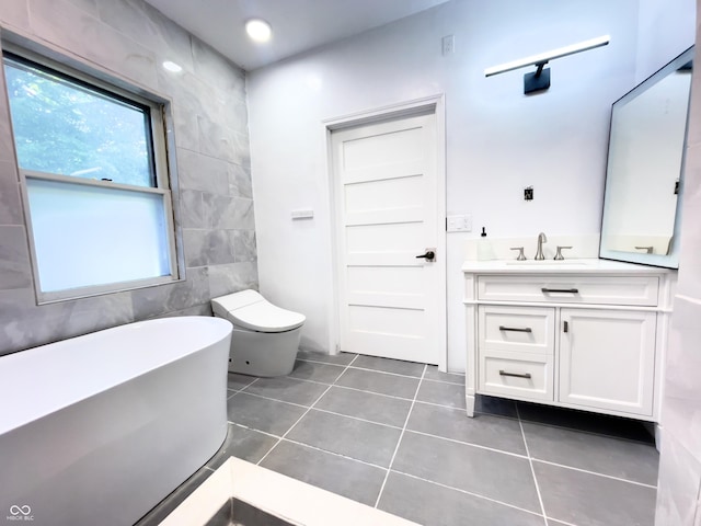 bathroom with toilet, vanity, tile walls, tile patterned floors, and a bathing tub