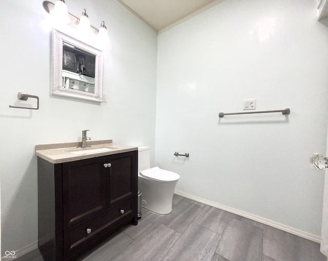 bathroom with toilet, ornamental molding, and vanity