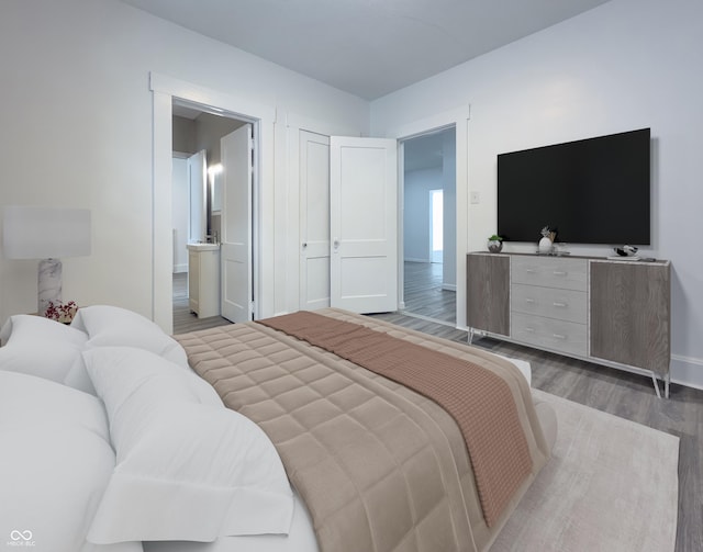 bedroom featuring connected bathroom and wood-type flooring