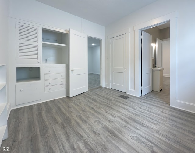 unfurnished bedroom featuring a closet, connected bathroom, and hardwood / wood-style floors