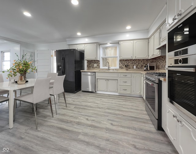 kitchen featuring white cabinetry, appliances with stainless steel finishes, tasteful backsplash, light wood-type flooring, and sink