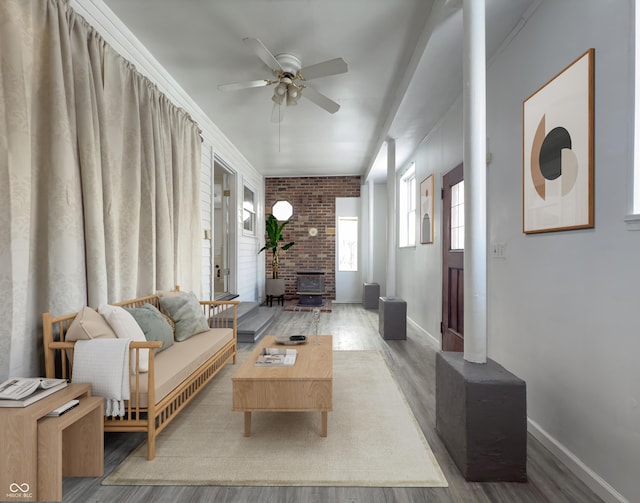 living room featuring ceiling fan, crown molding, a wood stove, and hardwood / wood-style flooring