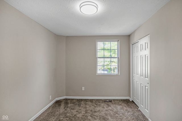 unfurnished room with carpet and a textured ceiling