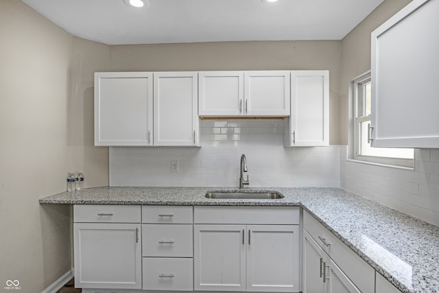 kitchen featuring sink, white cabinets, decorative backsplash, and light stone countertops