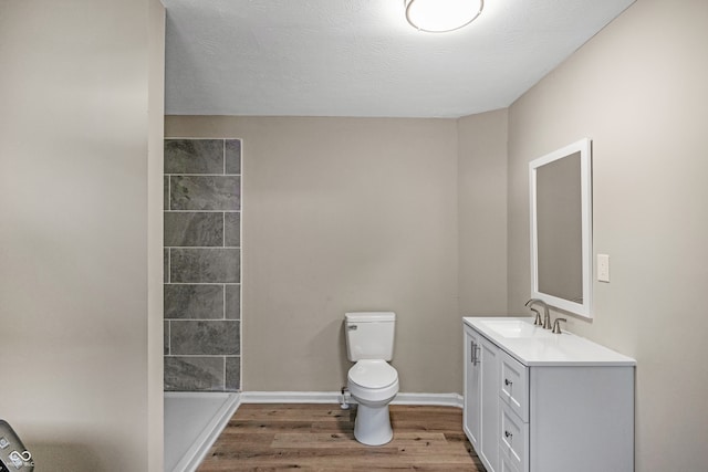 bathroom with vanity, toilet, wood-type flooring, and a textured ceiling