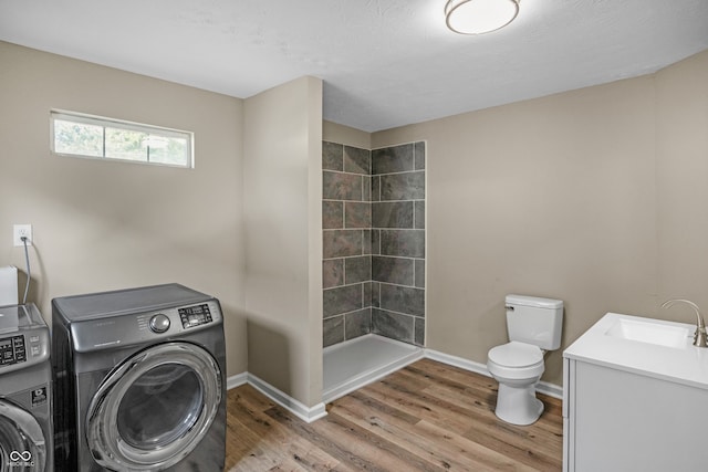 washroom with sink, separate washer and dryer, and hardwood / wood-style floors