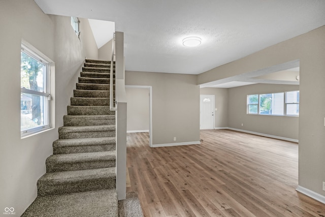 stairway with light hardwood / wood-style flooring and a wealth of natural light