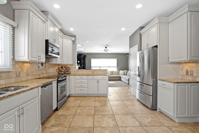 kitchen with ceiling fan, open floor plan, stainless steel appliances, white cabinetry, and light tile patterned flooring