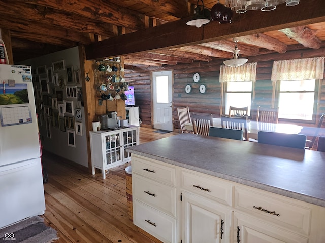 kitchen featuring beamed ceiling, freestanding refrigerator, light countertops, light wood-type flooring, and white cabinetry