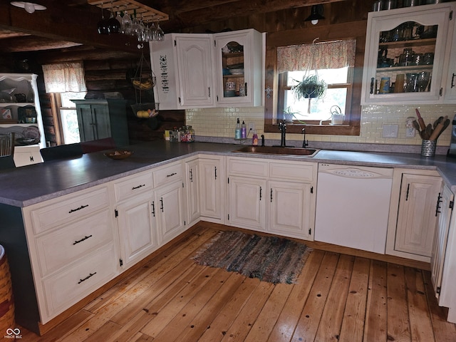 kitchen featuring a sink, white cabinetry, dishwasher, dark countertops, and glass insert cabinets