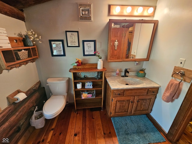 half bathroom featuring toilet, wood finished floors, vanity, and baseboards