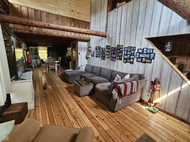 living room with stairs, wood walls, wood finished floors, and a towering ceiling