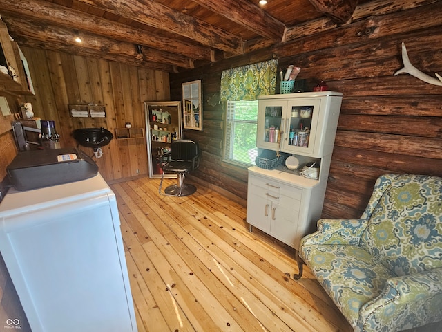 interior space featuring beam ceiling, glass insert cabinets, light wood-style floors, white cabinetry, and wooden ceiling