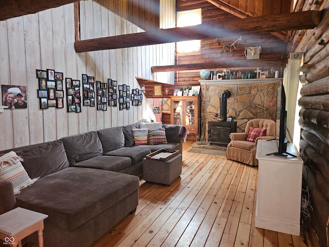 living room featuring light wood-style flooring, wooden walls, a towering ceiling, rustic walls, and a wood stove