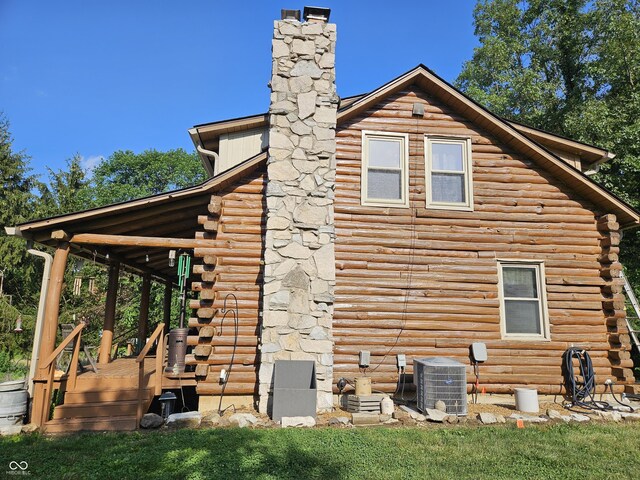 view of side of property featuring a deck, central AC, a chimney, and log siding