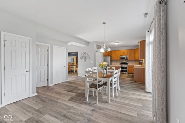 dining space featuring sink, an inviting chandelier, and light wood-type flooring