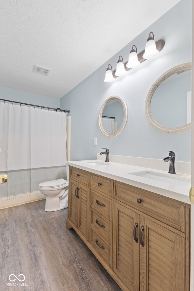 bathroom with a textured ceiling, vanity, toilet, a shower with shower curtain, and hardwood / wood-style flooring