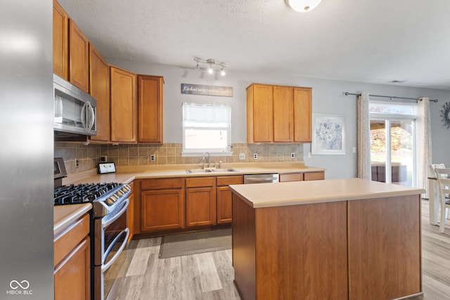 kitchen with a kitchen island, stainless steel appliances, plenty of natural light, sink, and light hardwood / wood-style flooring