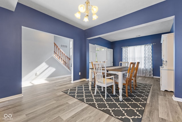 dining space featuring wood-type flooring and a chandelier