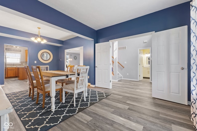 dining space with light hardwood / wood-style floors, sink, and a notable chandelier