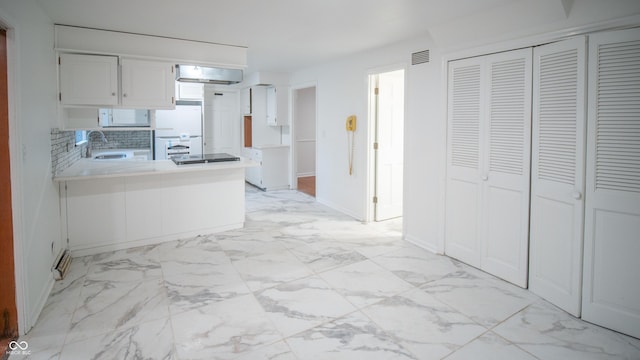 kitchen with tasteful backsplash, white cabinetry, sink, white refrigerator, and kitchen peninsula