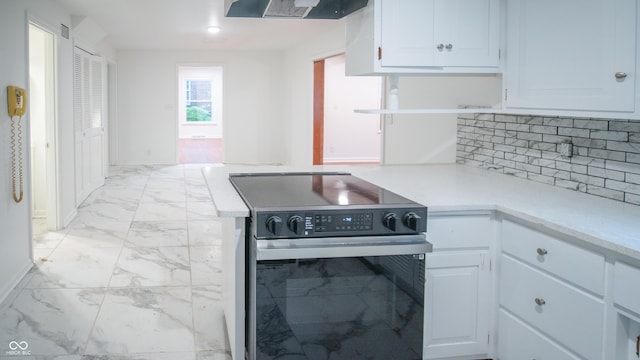 kitchen with tasteful backsplash, stainless steel electric range, exhaust hood, and white cabinets