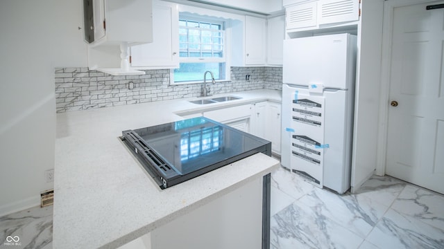 kitchen with tasteful backsplash, sink, white fridge, and white cabinets