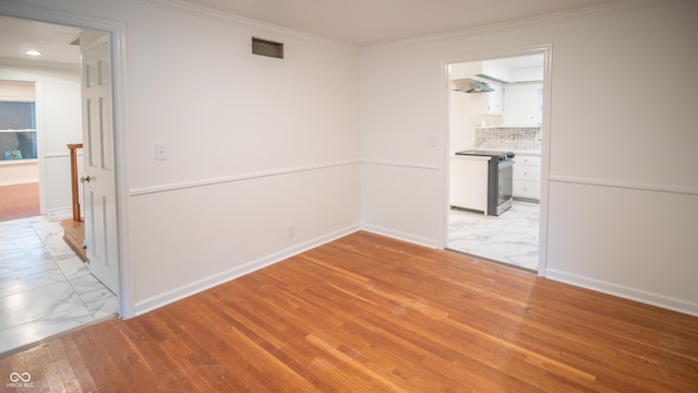 empty room with crown molding and light hardwood / wood-style floors