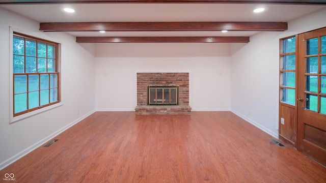 unfurnished living room with wood-type flooring, a fireplace, and beam ceiling