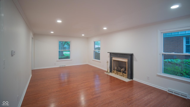 unfurnished living room with hardwood / wood-style flooring and crown molding