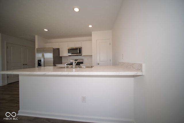 kitchen with sink, dark wood-type flooring, appliances with stainless steel finishes, white cabinetry, and kitchen peninsula