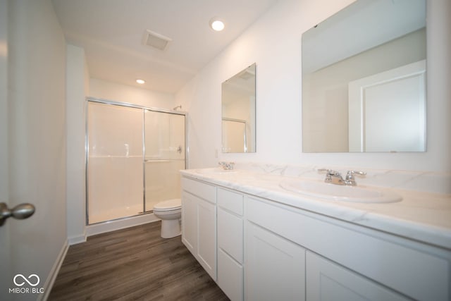 bathroom featuring toilet, hardwood / wood-style floors, vanity, and a shower with shower door