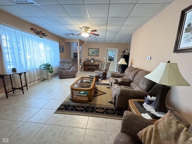 living room featuring a paneled ceiling, ceiling fan, and light tile patterned flooring