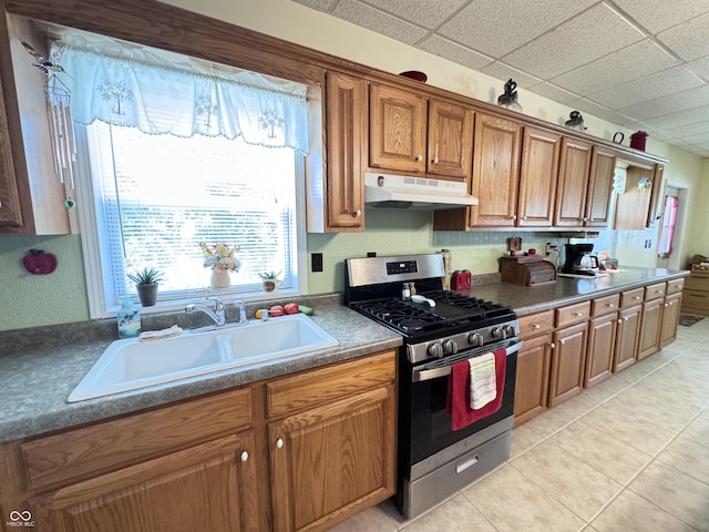 kitchen featuring light tile patterned flooring, a drop ceiling, sink, and stainless steel gas range oven