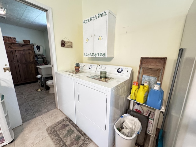 clothes washing area with washing machine and dryer and light tile patterned floors