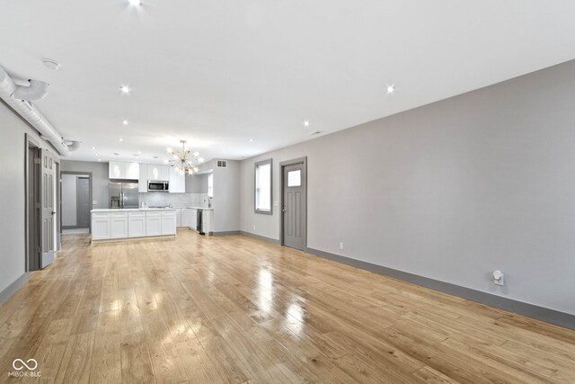 unfurnished living room with light hardwood / wood-style floors and a chandelier