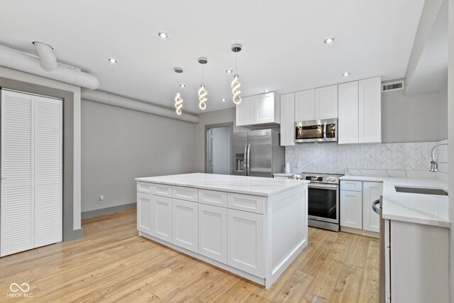 kitchen with stainless steel appliances, white cabinets, tasteful backsplash, and light hardwood / wood-style flooring