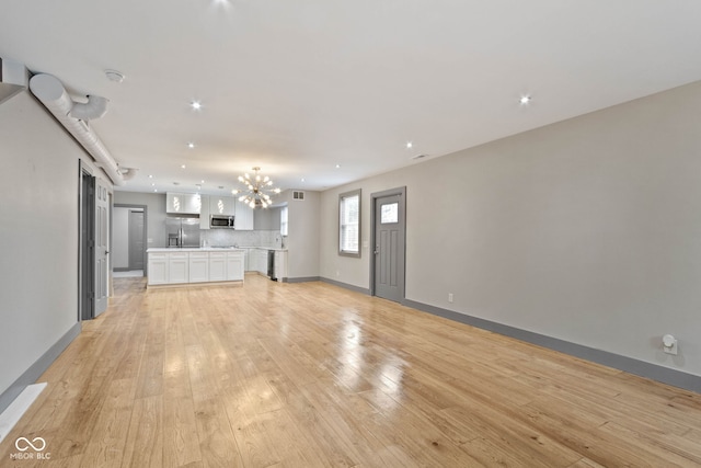 unfurnished living room with light hardwood / wood-style floors and a notable chandelier