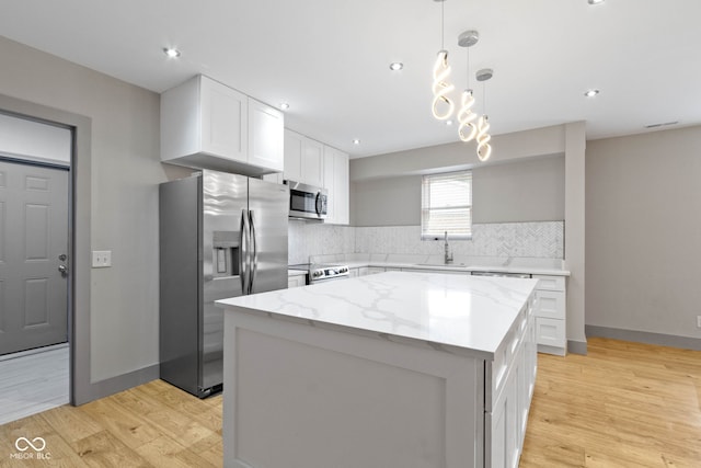 4513 Norwaldo Ave, Indianapolis, IN 46205 - kitchen featuring decorative light fixtures, white cabinetry, a center island, stainless steel appliances, and light stone countertops