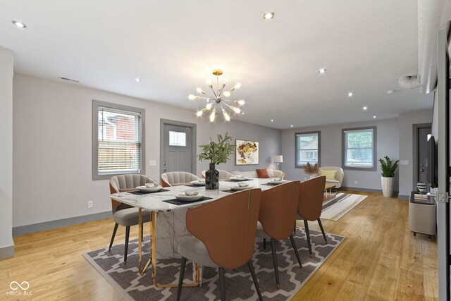 dining area with light wood-type flooring and a chandelier