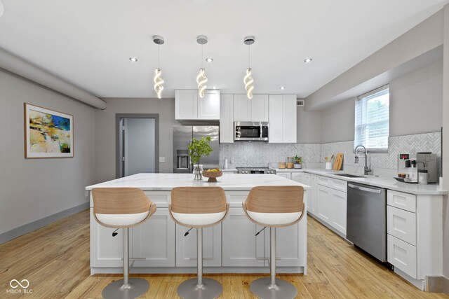 kitchen with decorative backsplash, white cabinetry, appliances with stainless steel finishes, and a kitchen island