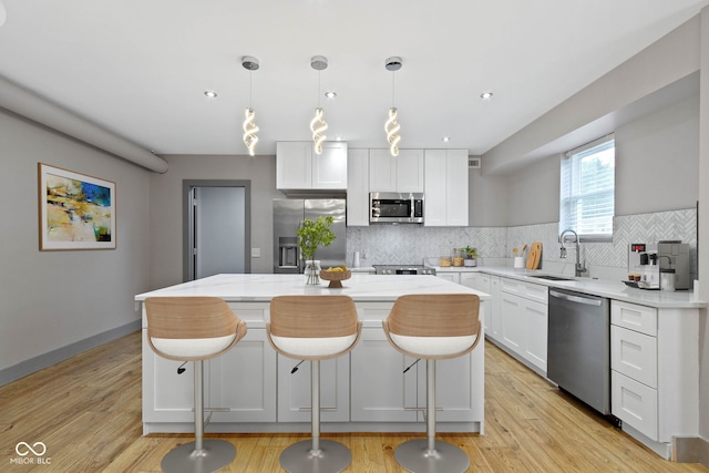 4513 Norwaldo Ave, Indianapolis, IN 46205 - kitchen with decorative light fixtures, white cabinetry, sink, a center island, and stainless steel appliances