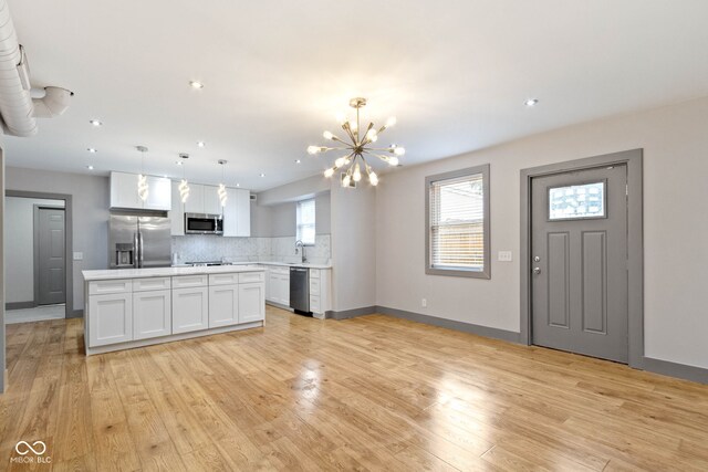 kitchen featuring tasteful backsplash, white cabinetry, light hardwood / wood-style floors, and stainless steel appliances