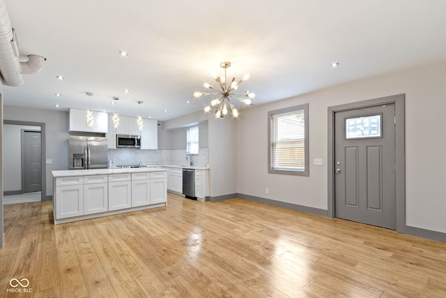4513 Norwaldo Ave, Indianapolis, IN 46205 - kitchen with stainless steel appliances, pendant lighting, white cabinets, and light hardwood / wood-style flooring