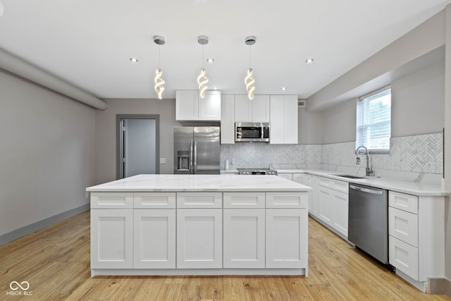 4513 Norwaldo Ave, Indianapolis, IN 46205 - kitchen featuring sink, white cabinetry, hanging light fixtures, stainless steel appliances, and a center island