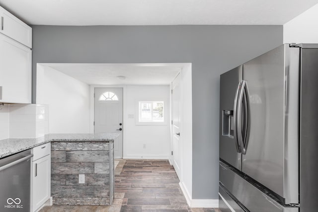 kitchen featuring decorative backsplash, white cabinets, light stone counters, dark hardwood / wood-style floors, and appliances with stainless steel finishes