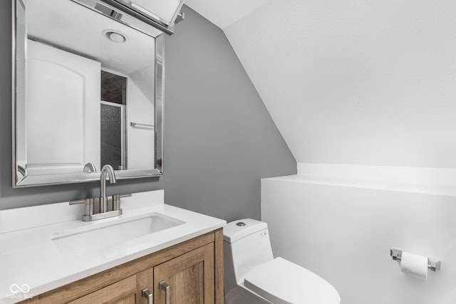 bathroom with vanity, toilet, and lofted ceiling